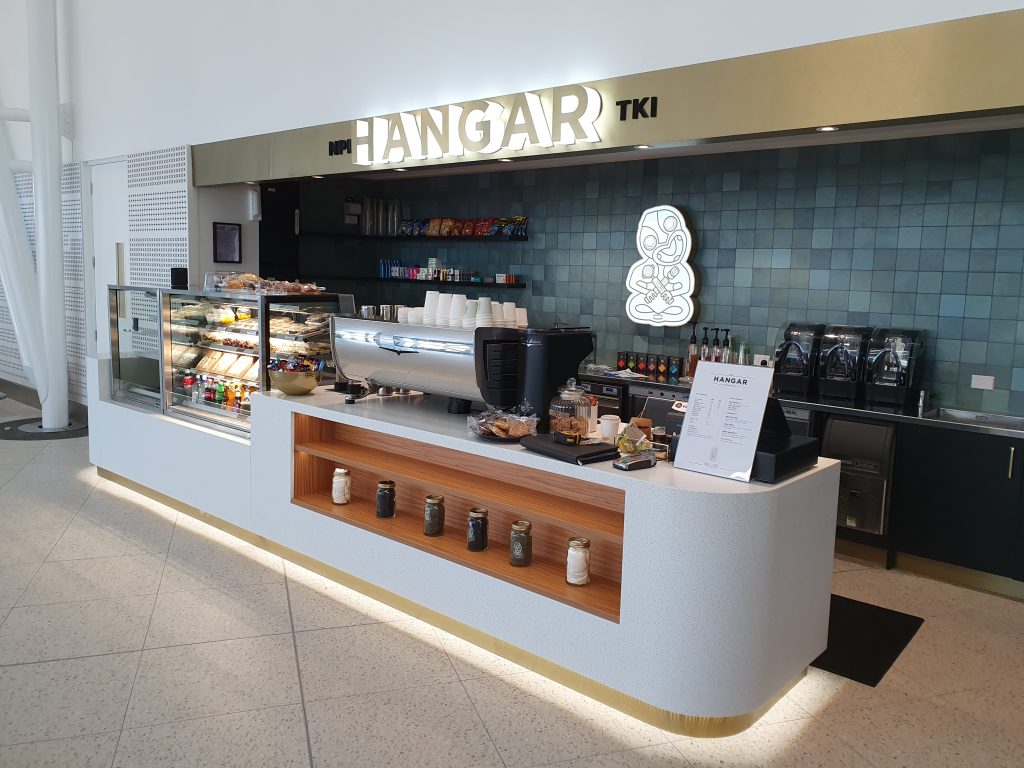 Custom café joinery by Newton Gordge Joinery at New Plymouth Airport’s Hangar TKI, featuring modern counters, display units, and tiled backsplash.