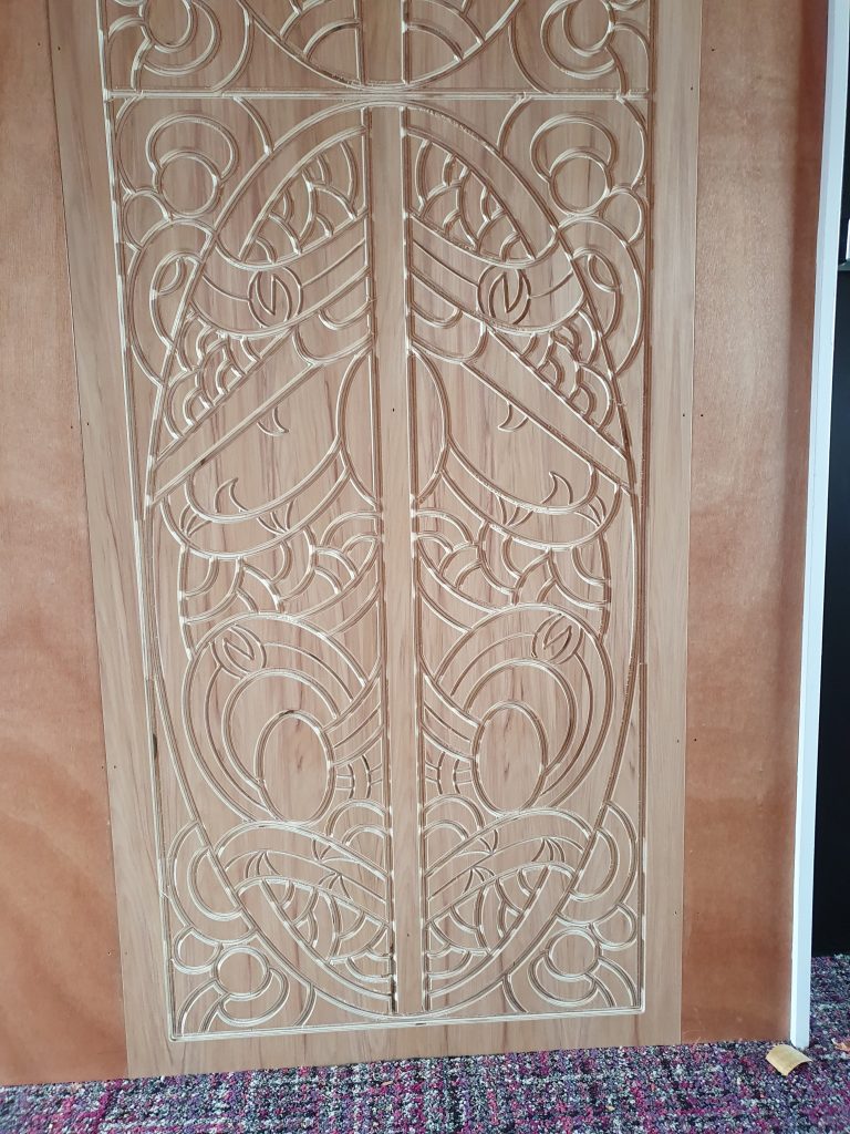 Custom CNC-carved timber panels featuring intricate Māori-inspired patterns installed on a rustic timber wall in a local Marae, showcasing detailed craftsmanship for interior feature walls and architectural joinery.