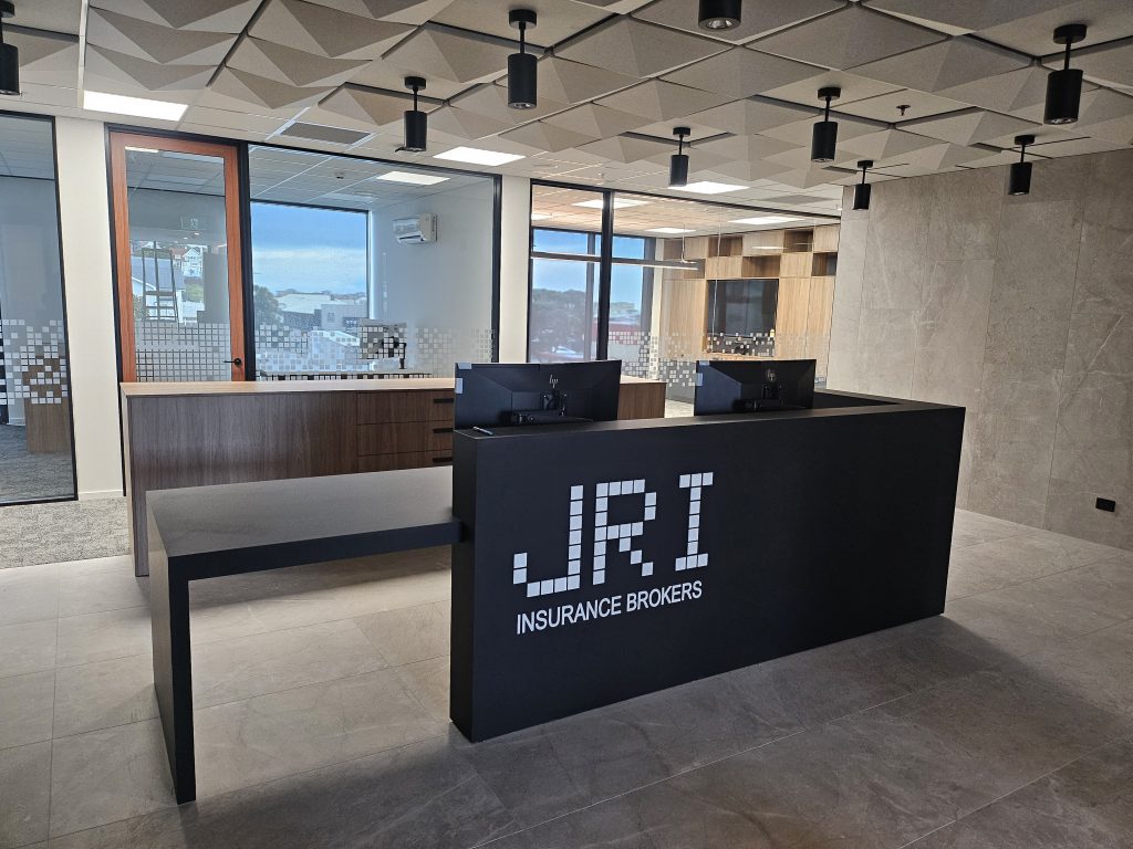 Modern commercial reception desk with integrated workspace, custom-built by Newton Gordge Joinery for JRI Insurance Brokers in New Plymouth.